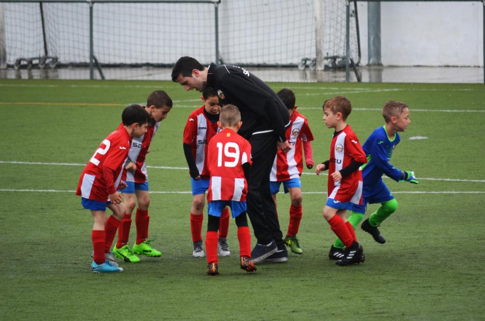  jonge voetballers met hun coach op voetbalveld