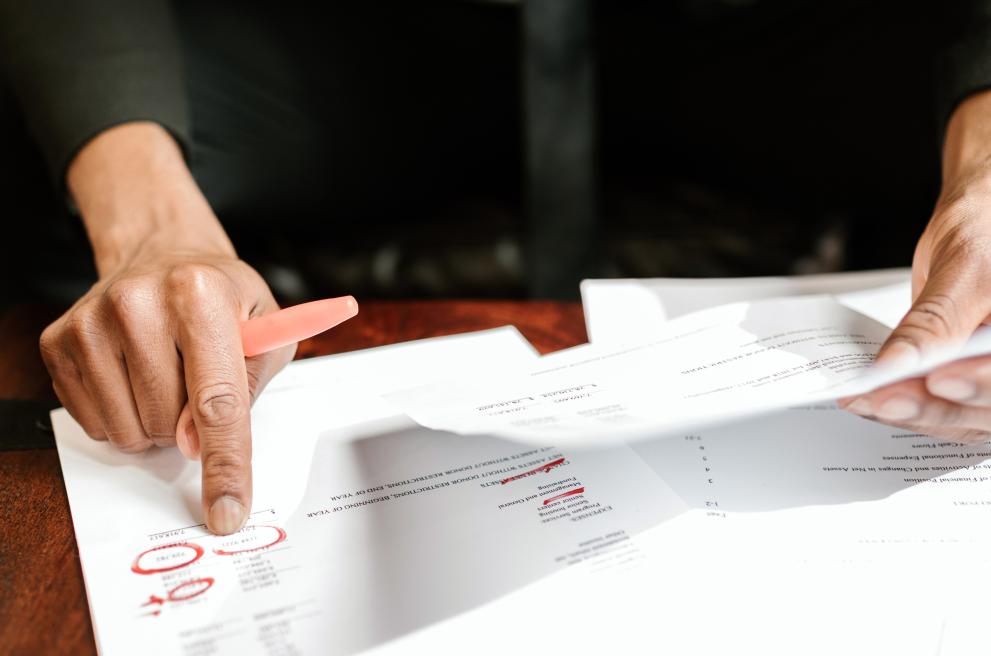 Man met balpen in de hand die papieren vergelijkt