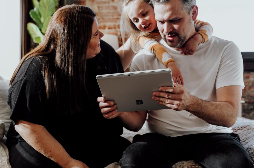 Gezin van drie kijkt naar tablet en ziet er opgelucht en blij uit